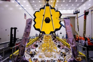 The James Webb Space Telescope floating in deep space, with its golden hexagonal mirrors reflecting cosmic light.